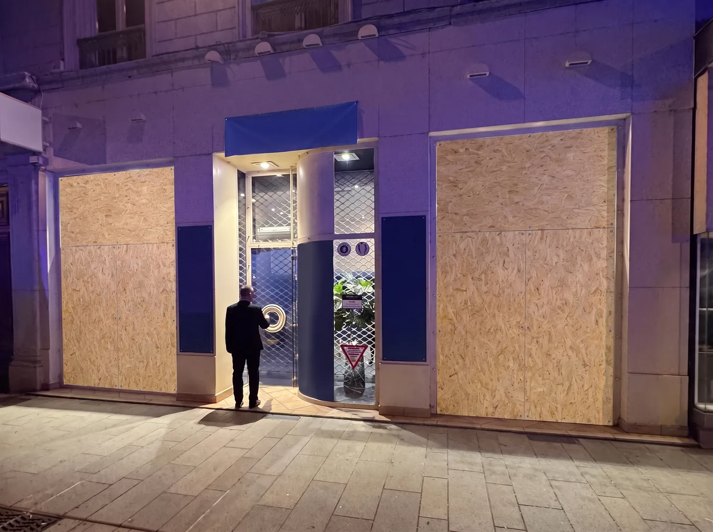 Le même commerce, les deux baies fermées par des panneaux OSB
