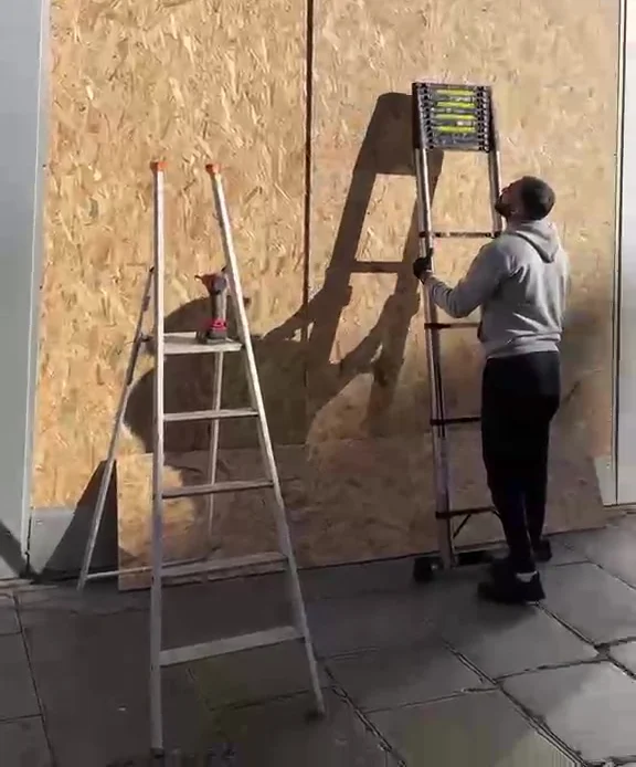 Poseur devant une devanture fermée par des panneaux OSB